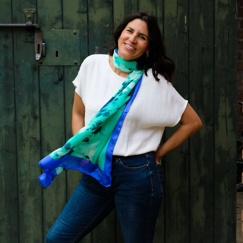 woman smiling wearing louis jane long silk scarf in mint and cerulean blue colour, summer branches design