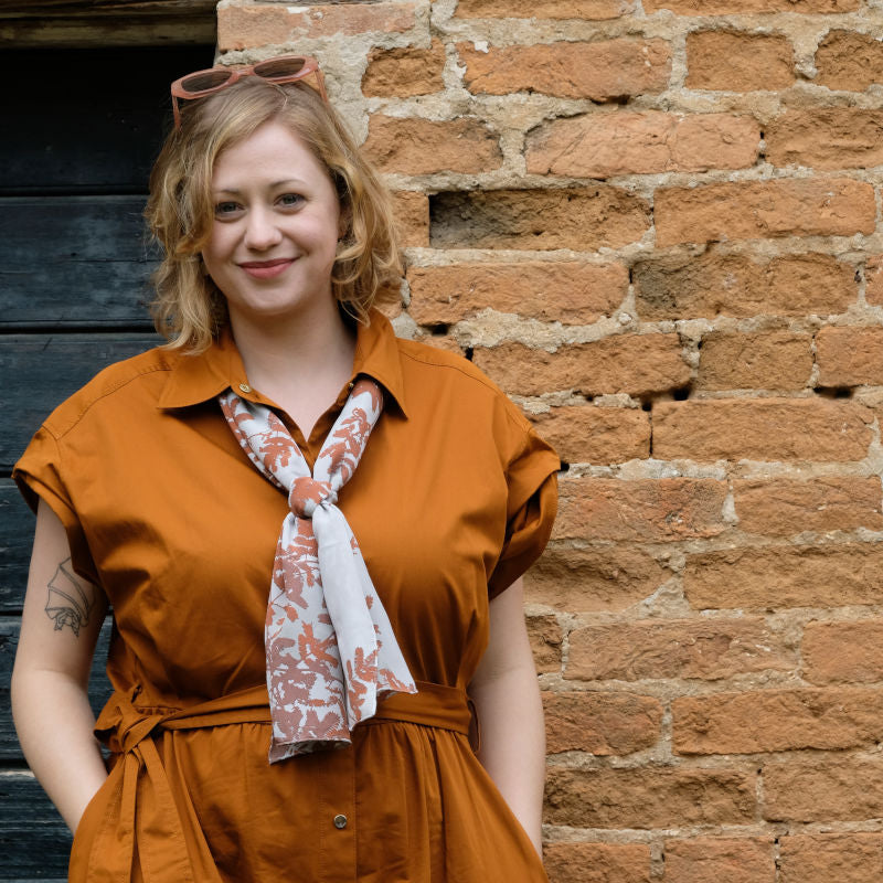 Woman wearing Fern Sprays long silk scarf in Russet and Cool Blue colour under collar of shirt dress